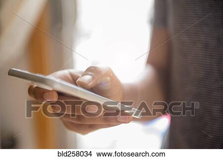 Picture - Hand of African American woman texting on cell phone. Fotosearch