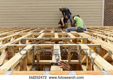 Stock Image - Hand reaching for hammer on the roof at construction site. Fotosearch