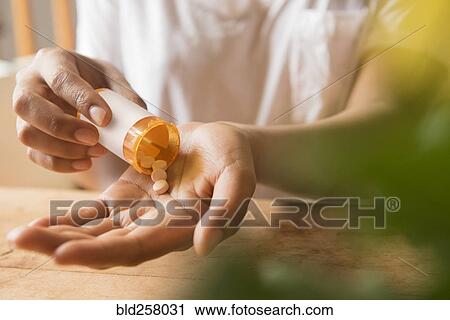 Stock Image - Hands of African American woman holding prescription medicine. Fotosearch