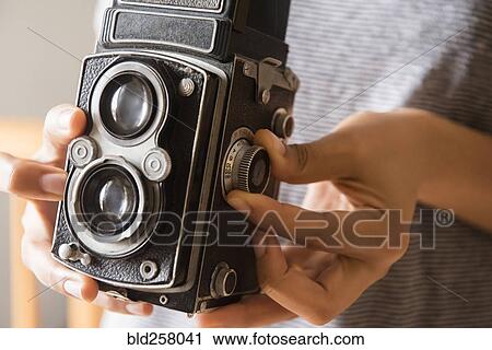 Stock Image - Hands of African American woman using old-fashioned camera. Fotosearch
