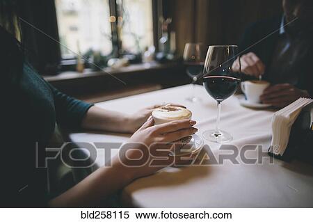 Stock Photography - Hands of Caucasian couple drinking coffee and wine. Fotosearch