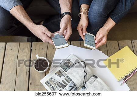 Stock Photo - Hands of Caucasian couple texting on cell phones. Fotosearch