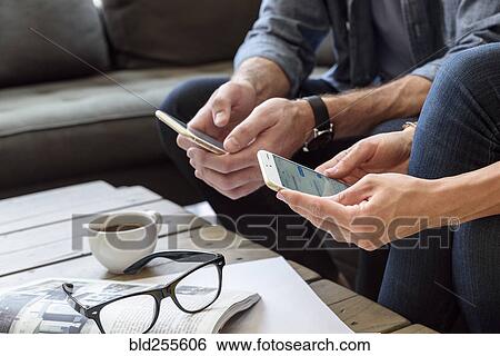 Stock Photograph - Hands of Caucasian couple texting on cell phones. Fotosearch