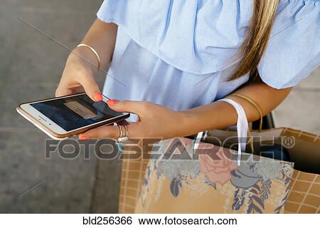 Hands of Caucasian woman carrying shopping bags texting on cell phone View Large Photo Image Stock Photograph - Hands of Caucasian woman carrying shopping bags texting on cell phone. Fotosearch