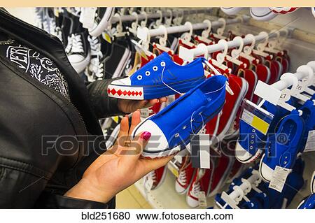 Stock Image - Hands of Caucasian woman holding sneakers in store. Fotosearch
