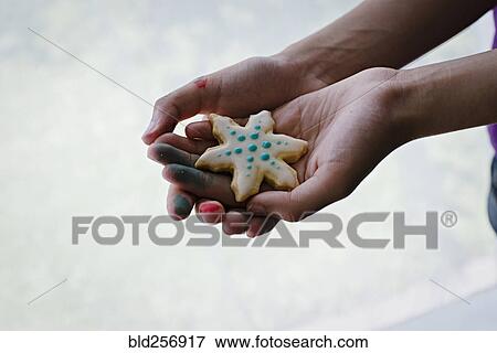 Stock Photo - Hands of mixed race girl showing Christmas cookie. Fotosearch