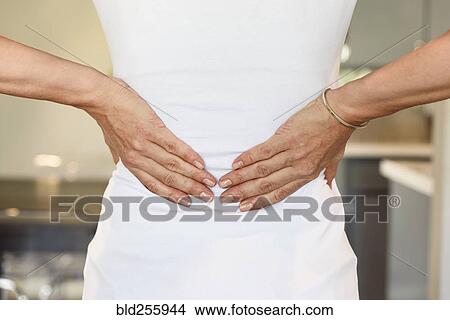 Picture - Hands of mixed race woman rubbing lower back. Fotosearch