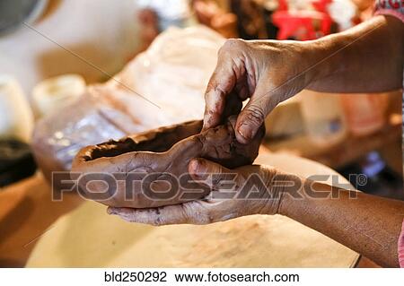 Stock Image - Hands of mixed race woman shaping clay in art studio. Fotosearch