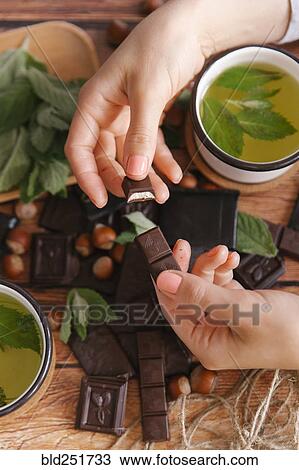 Hands of woman breaking chocolate near green tea View Large Photo Image Stock Image - Hands of woman breaking chocolate near green tea. Fotosearch
