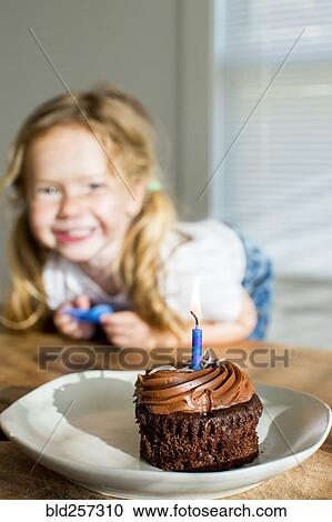 Stock Image - Happy Caucasian girl near birthday cupcake. Fotosearch