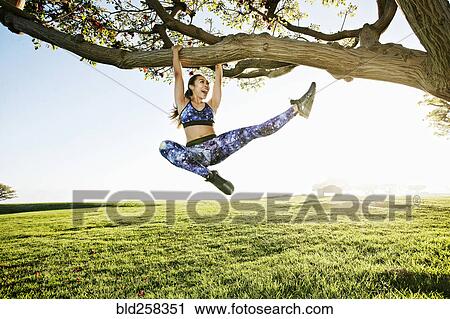 Happy mixed race woman hanging on tree branch View Large Photo Image Stock Image - Happy mixed race woman hanging on tree branch. Fotosearch