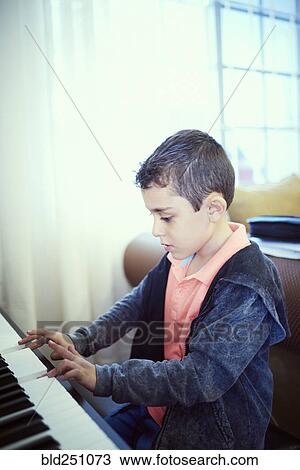 Stock Image - Hispanic boy playing piano. Fotosearch