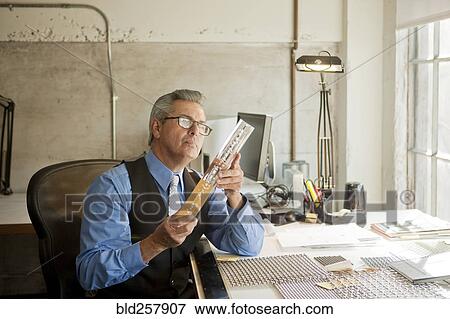 Hispanic businessman in office examining part View Large Photo Image Stock Photo - Hispanic businessman in office examining part. Fotosearch