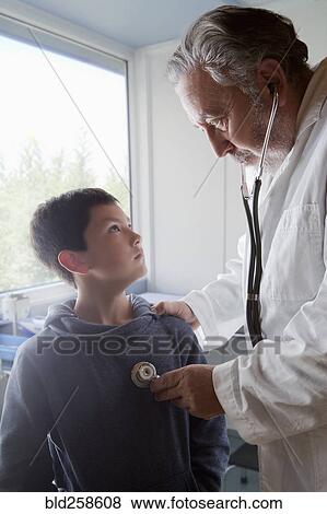 Stock Photo - Hispanic doctor listening to chest of boy with stethoscope. Fotosearch