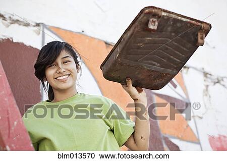 Stock Image - Hispanic girl painting wall. Fotosearch