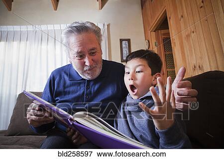 Stock Photo - Hispanic grandfather and excited grandson reading book. Fotosearch