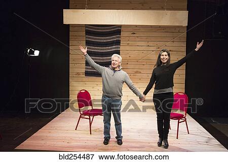 Stock Photo - Hispanic man and woman holding hands on theater stage. Fotosearch