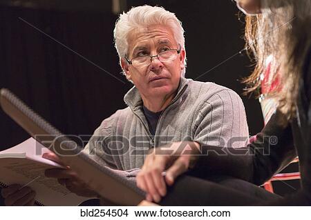 Picture - Hispanic man and woman reading scripts in theater. Fotosearch