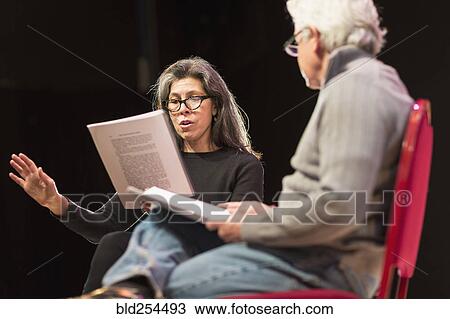 Stock Image - Hispanic man and woman reading scripts on theater stage. Fotosearch