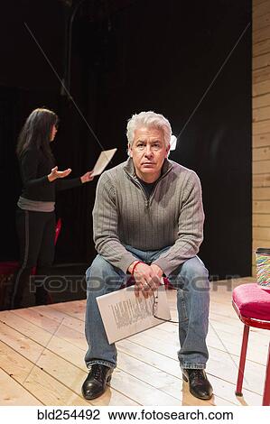 Stock Image - Hispanic man holding script on theater stage. Fotosearch
