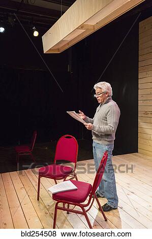 Stock Photo - Hispanic man reading script on theater stage. Fotosearch