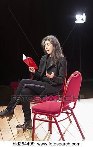 Stock Photo - Hispanic woman reading script on theater stage. Fotosearch