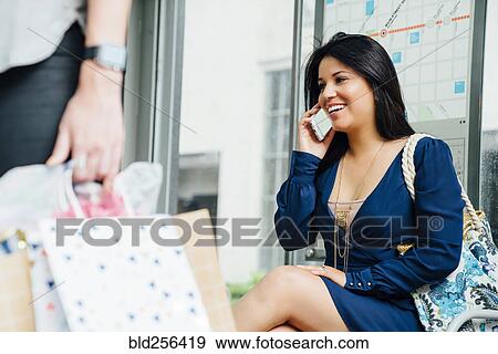 Hispanic woman sitting at train station talking on cell phone View Large Photo Image Stock Photo - Hispanic woman sitting at train station talking on cell phone. Fotosearch