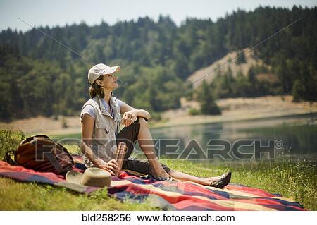 Hispanic woman sitting on picnic blanket near lake View Large Photo Image Stock Photograph - Hispanic woman sitting on picnic blanket near lake. Fotosearch