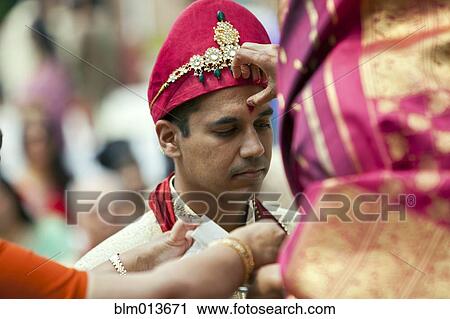 Stock Image - Indian woman marking groom's forehead. Fotosearch