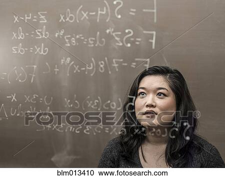 Stock Image - Korean student looking at formula on glass wall. Fotosearch