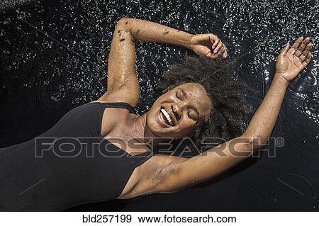 Laughing black woman laying in water View Large Photo Image Stock Photo - Laughing black woman laying in water. Fotosearch