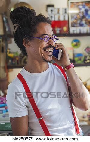 Laughing mixed race man wearing suspenders talking on cell phone View Large Photo Image Stock Photo - Laughing mixed race man wearing suspenders talking on cell phone. Fotosearch