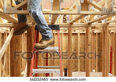 Stock Photography - Legs of black man on ladder at construction site. Fotosearch