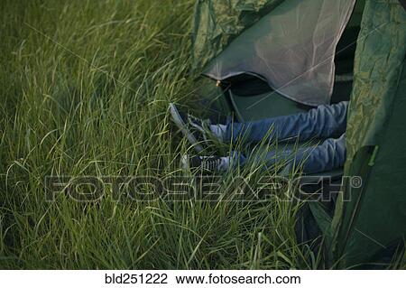 Stock Image - Legs of Caucasian man laying in tent. Fotosearch