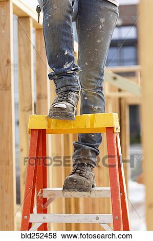 Stock Photo - Legs of Caucasian woman on ladder at construction site. Fotosearch