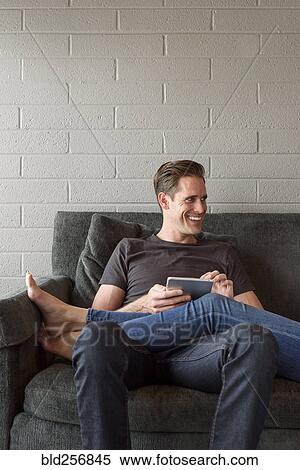 Stock Photography - Legs of Caucasian woman on lap of man using digital tablet. Fotosearch