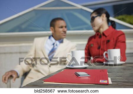 Stock Photo - Mail and coffee cups near couple talking outdoors. Fotosearch
