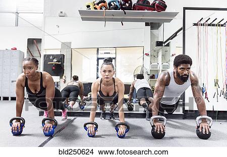 Man and women doing push-ups with kettlebells View Large Photo Image Picture - Man and women doing push-ups with kettlebells. Fotosearch