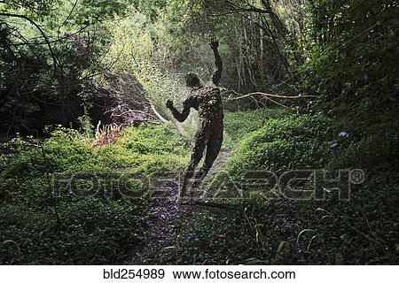 Stock Photo - Man covered with rocks with arms raised in forest. Fotosearch