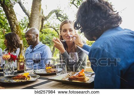 Picture - Man feeding food to woman at party outdoors. Fotosearch