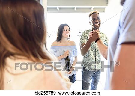 Stock Photo - Man greeting friends in doorway. Fotosearch