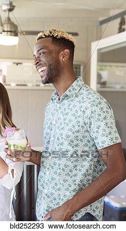Stock Image - Man holding cold drink laughing outdoors. Fotosearch