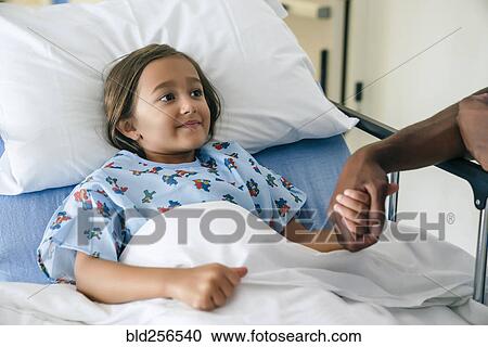 Stock Image - Man holding hands with girl in hospital bed. Fotosearch