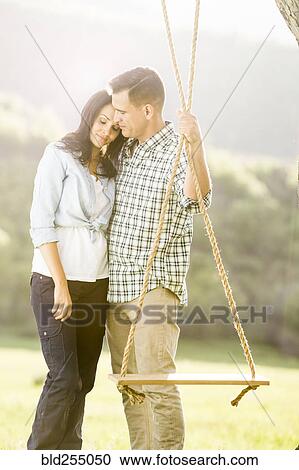 Man hugging woman and holding tree swing View Large Photo Image Stock Image - Man hugging woman and holding tree swing. Fotosearch