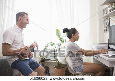 Man playing ukulele watching woman using computer View Large Photo Image Stock Image - Man playing ukulele watching woman using computer. Fotosearch