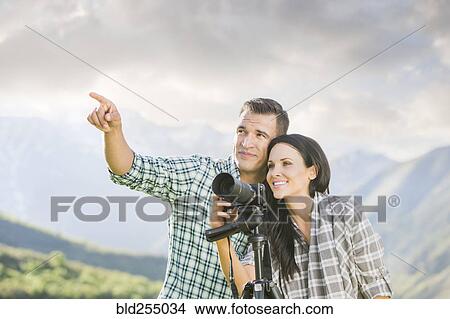 Picture - Man pointing for woman photographing with camera. Fotosearch