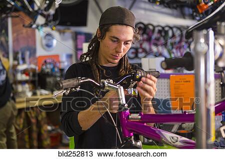 Stock Image - Man repairing bicycle in shop. Fotosearch