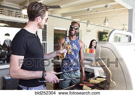 Men cooking on grille and toasting with beer outdoors View Large Photo Image Picture - Men cooking on grille and toasting with beer outdoors. Fotosearch