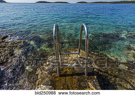 Stock Photo - Metal railing on rocks at ocean. Fotosearch