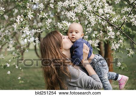 Picture - Middle eastern mother kissing son under flowering tree. Fotosearch